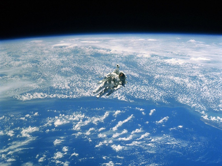 Astronauta ripreso in missione, con la Terra come sfondo